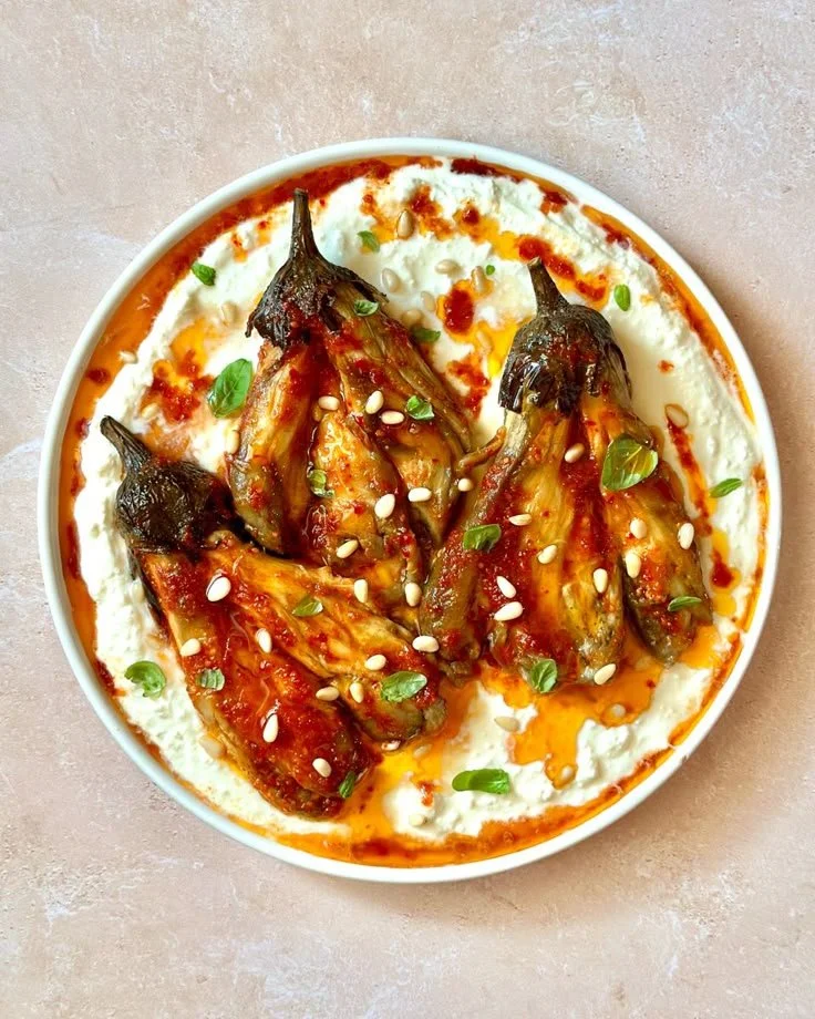 Grilled aubergines topped with feta cream and drizzled with harissa oil.