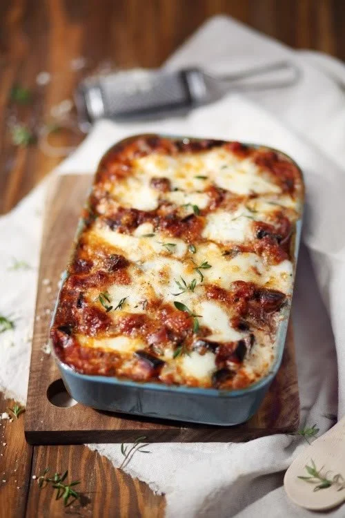 Gratin d'aubergines au parmesan et mozzarella présenté dans un plat en céramique.