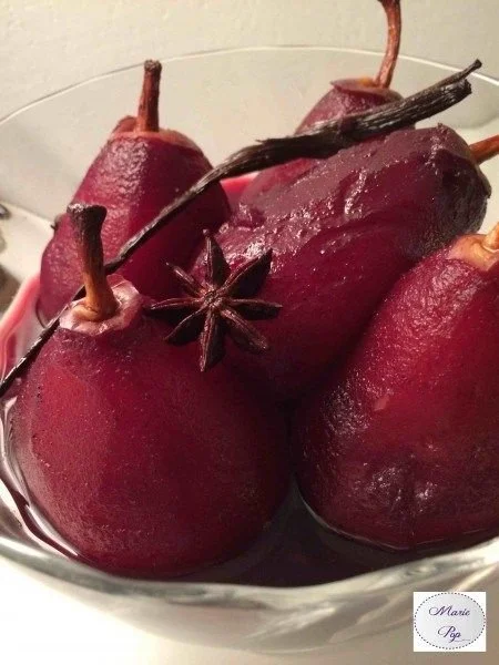 Poires au vin présentées dans un dessert élégant garnies d'épices.
